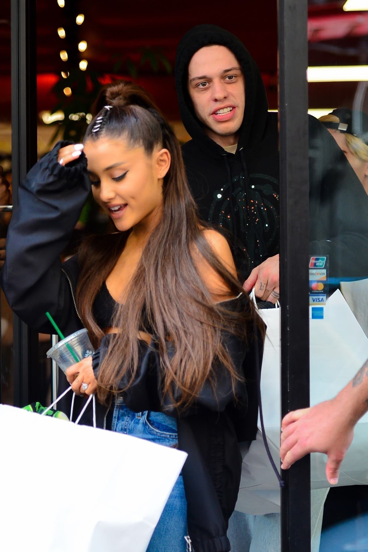 Photo © 2018 Backgrid/The Grosby Group Spain: Lagencia Grosby *EXCLUSIVE* New York, NY - Pop superstar Ariana Grande shows some skin as she and her fiancee, actor Pete Davidson, are spotted heading out for some shopping with friends in New York. Pete goes incognito with a bandana covering his face, as he steps out holding hands with his lovey girlfriend. The duo shared a LOT of PDA while enjoying their shopping spree. BACKGRID USA 28 JUNE 2018