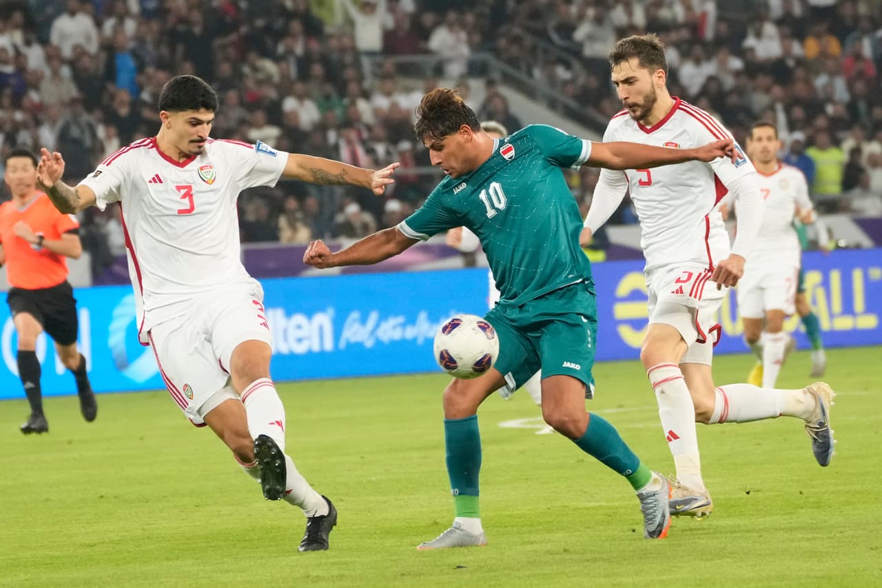 El iraquí Mohanad Ali (centro) y el emiratí Lucas Pimenta (izquierda) disputan el balón durante el partido de vuelta de la eliminatoria para la Copa Mundial de 2026 entre Irak y los Emiratos Árabes Unidos, en Basora, Irak, el martes 18 de noviembre de 2025.