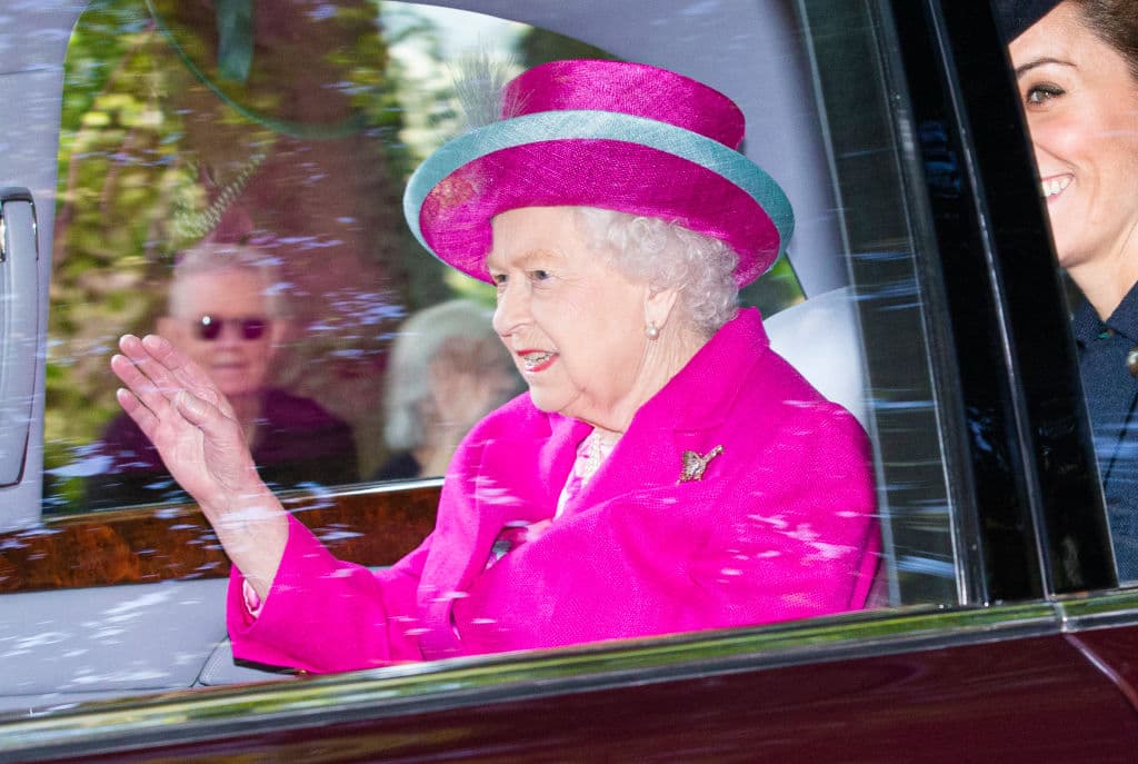La reina Isabel II optó por un traje fucsia brillante, con un sombrero del mismo tono con un borde azulado y una pequeña pluma al frente.