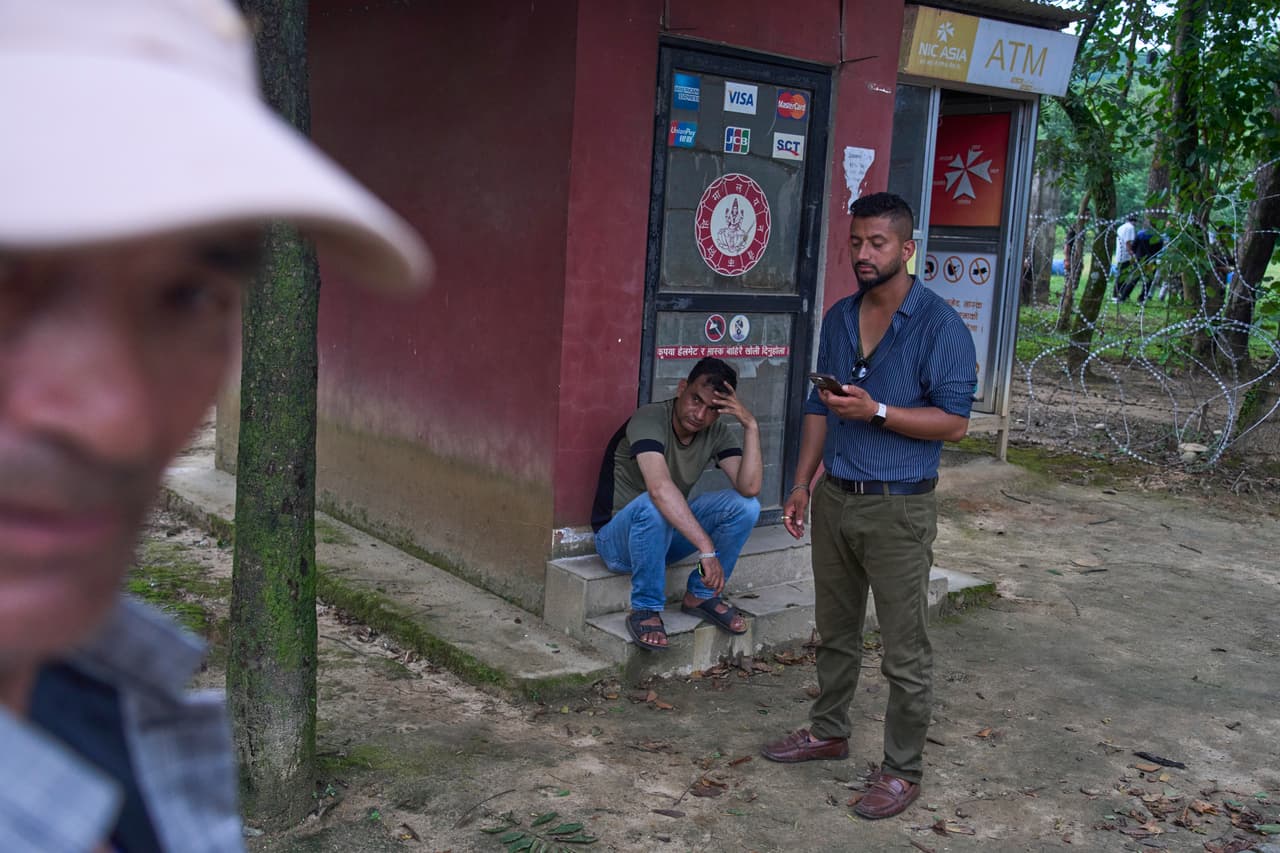 Personas esperan noticias de sus familiares desaparecidos tras las inundaciones repentinas a lo largo del río Trishuli.