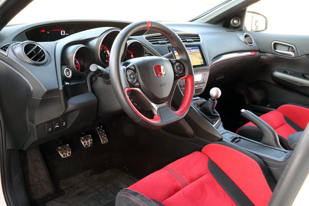 El interior del Civic Type R muestra algunos detalles que son específicos de esta versión, y no estarán disponibles en ninguna otra, como por ejemplo su volante (de dimensiones algo menores a lo habitual) y la combinación de colores en negro con rojo y sus costuras.