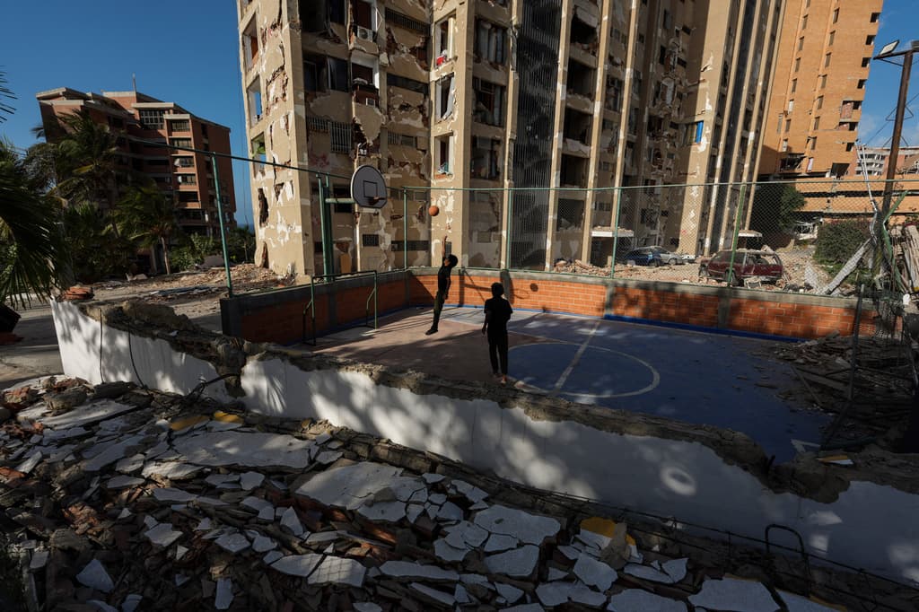 Unos niños juegan al baloncesto cerca de edificios destruidos por los terremotos que azotaron Catia La Mar, Venezuela, el lunes 29 de junio de 2026. (Foto AP/Matias Delacroix)