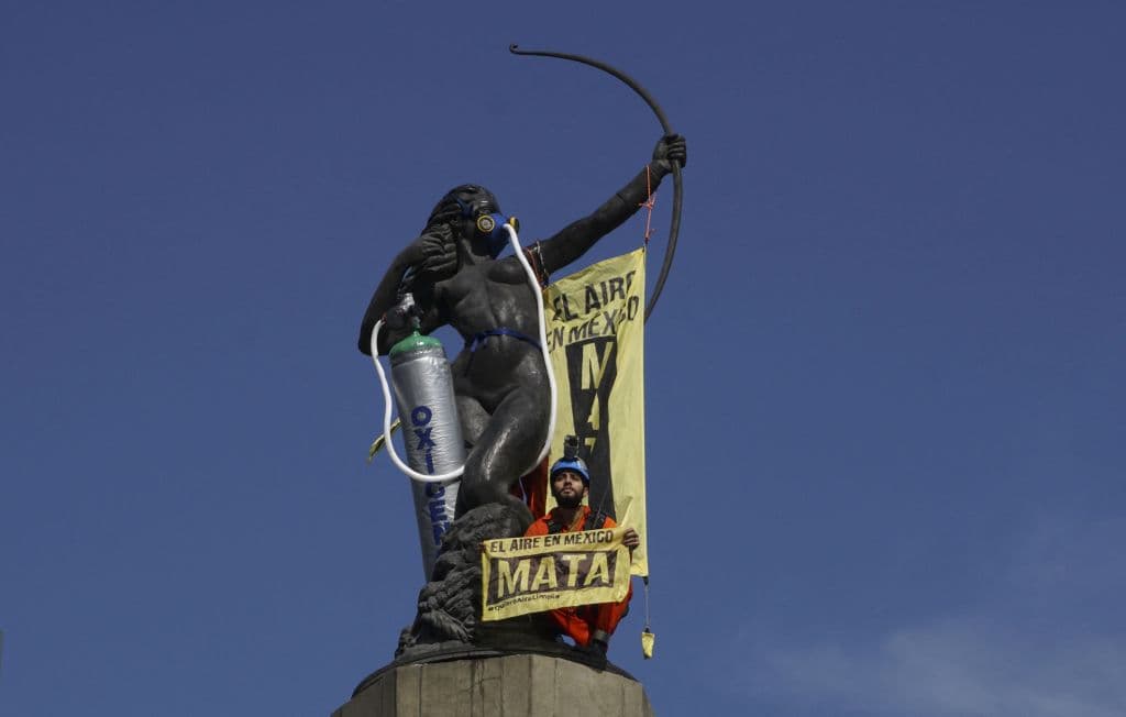 Un activista de la organización ambiental Greenpeace se manifiesta en el monumento La Diana Cazadora, donde instalaron un tanque de oxígeno y una máscara para protestar por la mala calidad del aire y la contaminación excesiva, en la Ciudad de México el 30 de mayo de 2018.