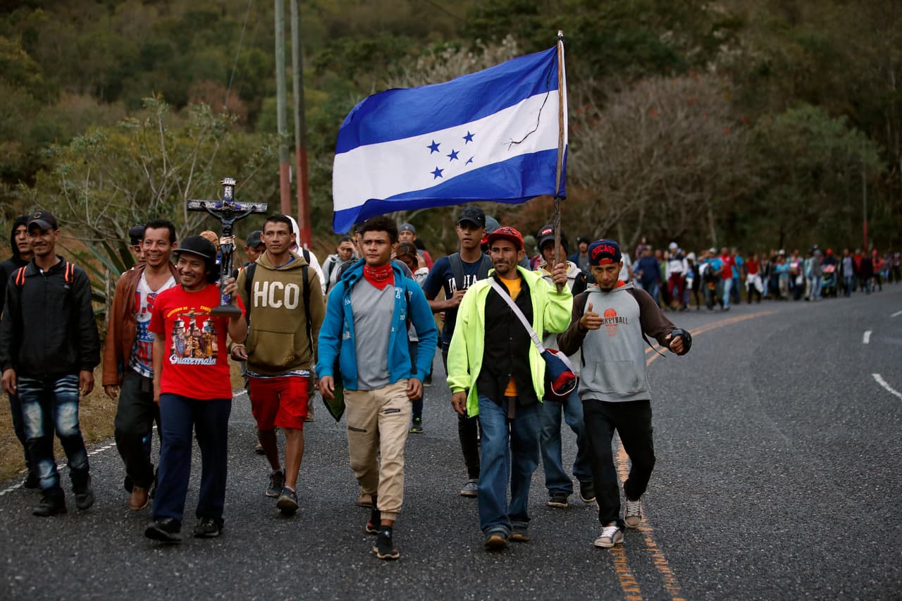 Un grupo de hondureños con una bandera de su país y un crucifijo mientras este viernes recorrían Esquipulas, en Guatemala, de camino a México.