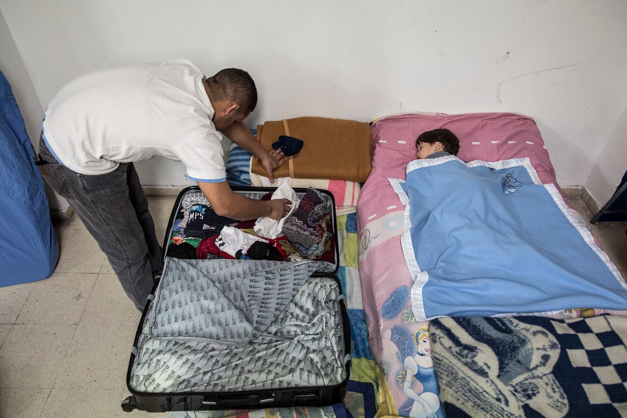 A Venezuelan father looks for clothes in a suitcase with his son, asleep on a mattress in the San Carlos Borromeo parish church. Before seeking refuge at the church this father and son, together with his seven months pregnant wife, spent a week sleeping on the streets of Madrid.