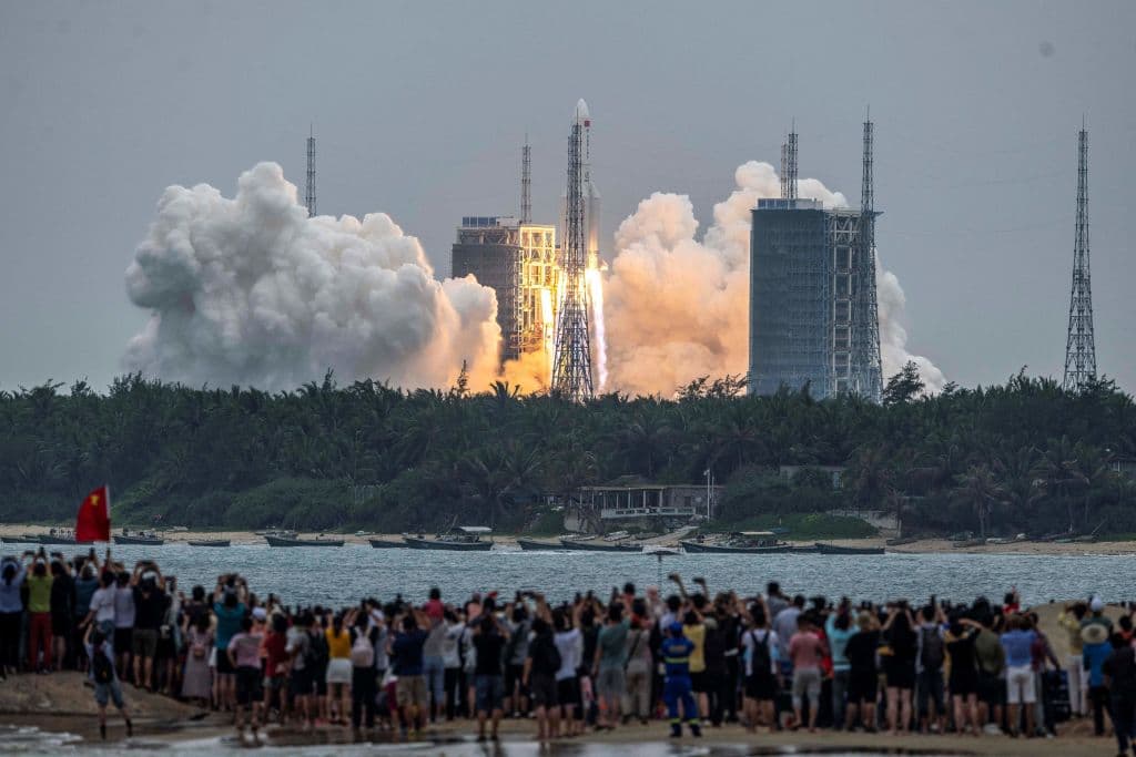 Una multitud observa la partida del cohete Long March 5B -Y2, que transporta el módulo central de la estación espacial Tianhe de China, mientras despega del Centro de Lanzamiento Espacial Wenchang en la provincia de Hainan, en el sur de China, el 29 de abril de 2021.