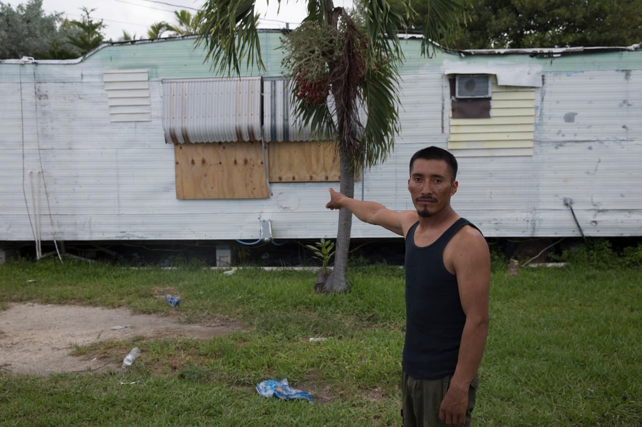 José López, un inmigrante mexicano de 31 años, muestra cómo él y sus compañeros colocaron planchas de madera en las ventanas del tráiler en el que viven.