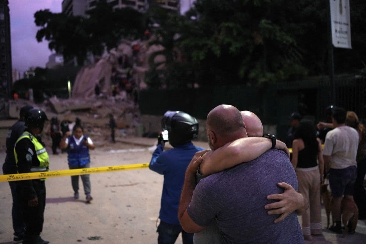 Vecinos observan la zona del derrumbe mientras continúan las operaciones de rescate y evaluación de daños.