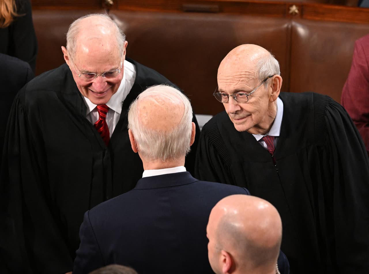 El presidente Joe Biden saluda a los jueces retirados de la Suprema Corte, Anthony Kennedy (izquierda) y Stephen Breyer (derecha), quienes fueron invitados al discurso en un gesto poco común para este tipo de mensajes.
