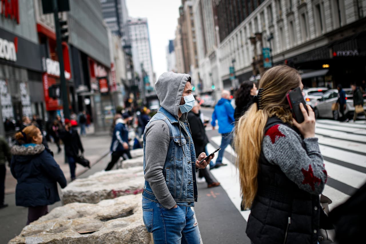 Un ciudadano de Nueva York usa camina por las calles de la ciudad, utilizando una máscara protectora.