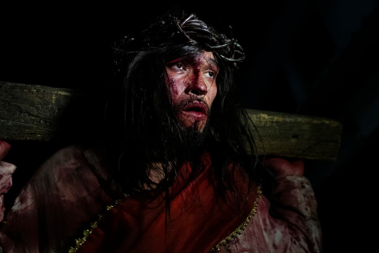 Luiz Henrique, interpretando a Jesucristo, carga una cruz durante una representación del Vía Crucis como parte de las celebraciones de Semana Santa, en la favela Complexo do Alemão en Río de Janeiro, el Viernes Santo, 18 de abril de 2025.
<br>