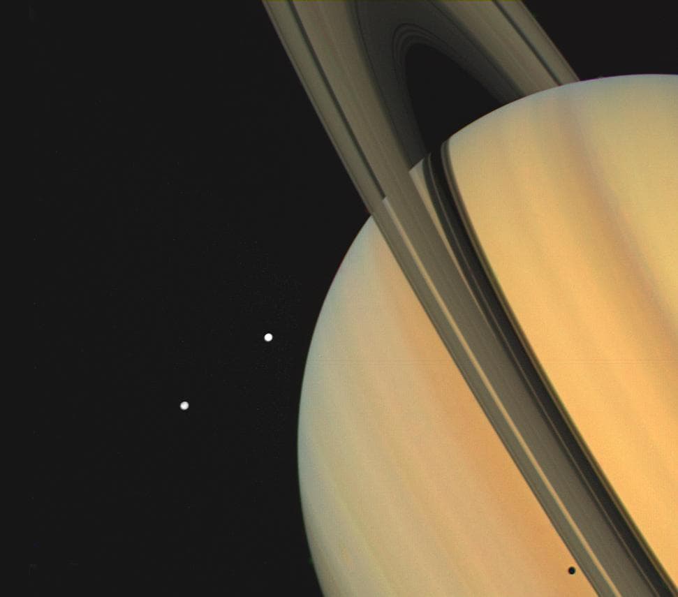 Esta es una imagen muestra al planeta Saturno junto a sus anillos y dos de sus lunas (Tetis y Dione), además de la sombra de una de ellas proyectada sobre el planeta. Fue capturada por la sonda Voyager 1 en 1980.