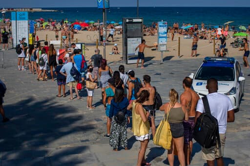 Personas esperaban en filas para entrar a la playa en Barcelona este sábado. La policía cerró el acceso.