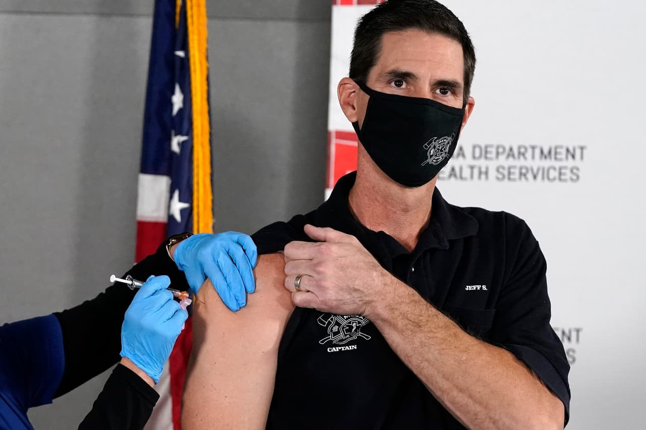 El capitán del Departamento de Bomberos de Mesa, Jeff Stieber,recibe la vacuna Pfizer-BioNTech contra el covid-19 en el Laboratorio Estatal del Departamento de Servicios de Salud de Arizona de manos de la enfermera Machrina Leach. La vacuna Pfizer dio un resultado del 95% de efectividad para prevenir que los pacientes contraigan el coronavirus y no causó efectos secundarios importantes en un ensayo de casi 44,000 personas.