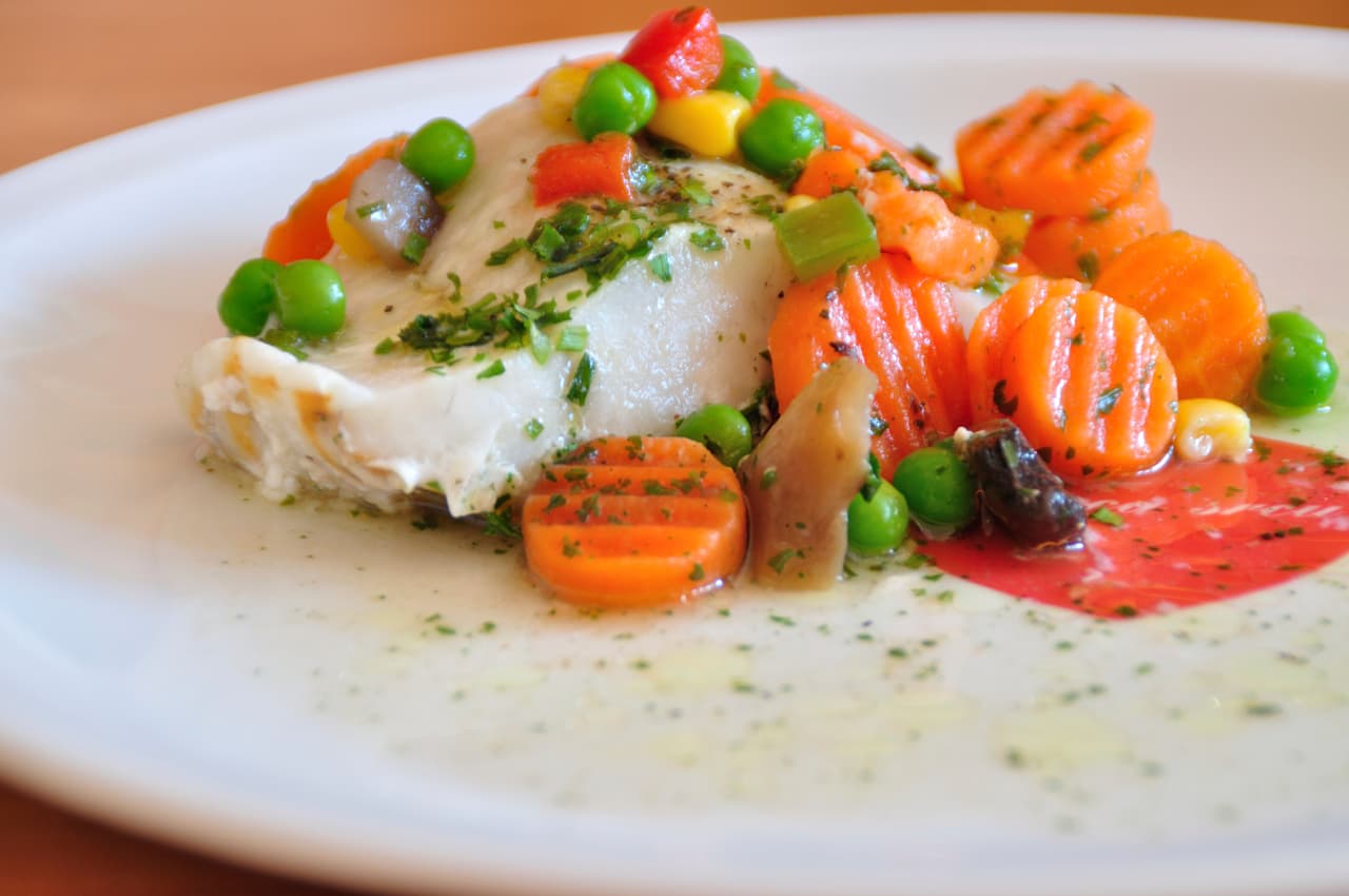 Debes calentar el aceite de oliva en el microondas y ahí mismo coloca los filetes de pescado después incorpora los dientes de ajo picados y el jugo de los limones. Cocina un par de minutos en el microondas y cuando esté cocinado, sirve el pescado con el perejil picado por encima.