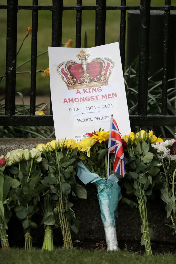 Una foto de Getty tomada el miércoles afuera del castillo de Windsor muestra arreglos florales y un gráfico con el mensaje ‘Un rey en medio de hombres’ al pie de una banderita británica, en homenaje al duque de Edimburgo.
