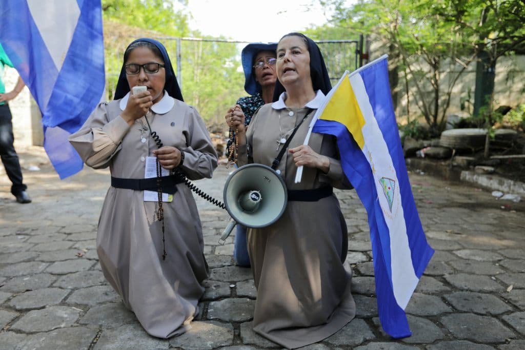 Una pareja de monjas portando banderas de Nicaragua rezan en la calle el 18 de mayo de 2018, durante el diálogo entre Ortega y la oposición.