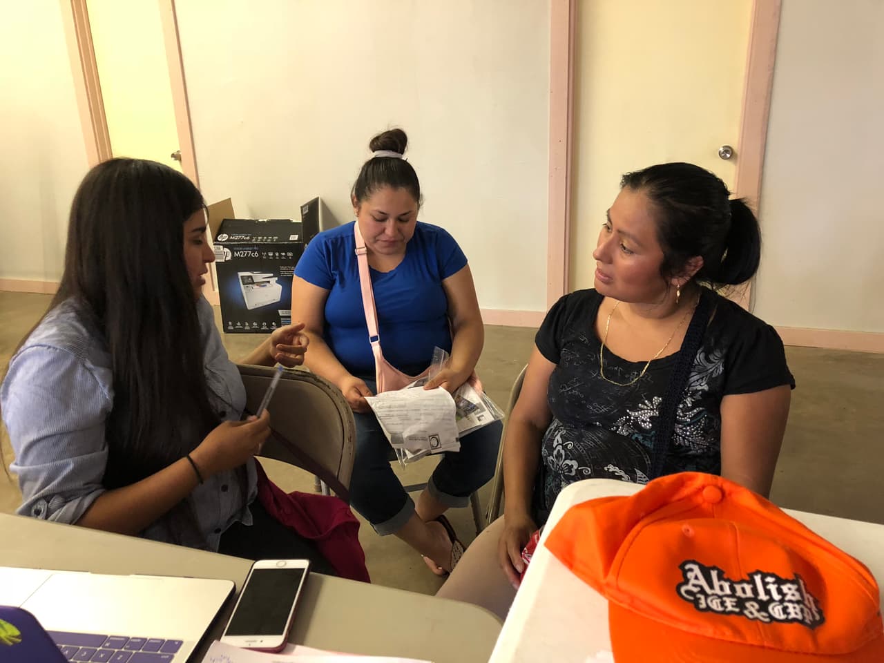 Laura Monroy (centro) y su cuñada Juana Ruiz (izq.) conversan con una voluntaria en la iglesia Fliadelfia de Paris, Texas. Organizaciones comunitarias están prestando ayuda a las familias afectadas por el operativo de ICE en el que cerca de 150 trabajadores fueron detenidos en una fábrica.