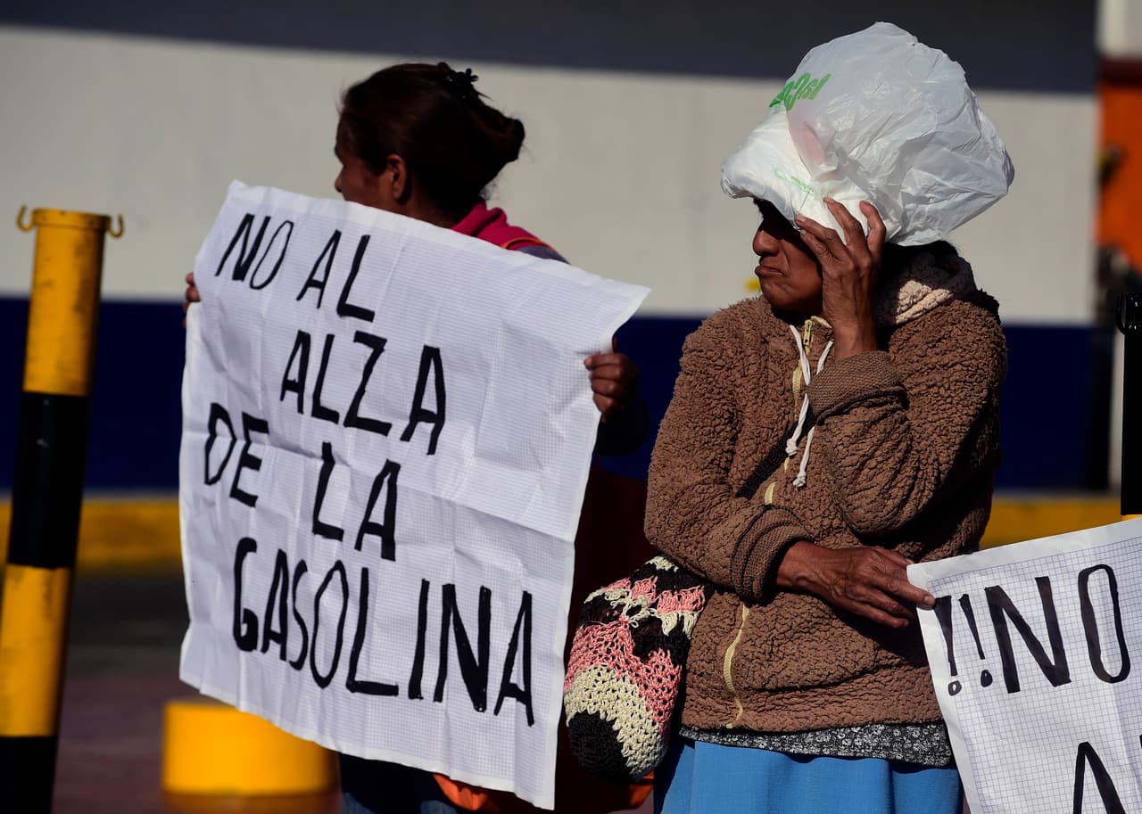 Algunas personas, portando pancartas con mensajes en contra del alza al precio de la gasolina, se manifestaron en las afueras de una estación de gasolina de la Ciudad de México.