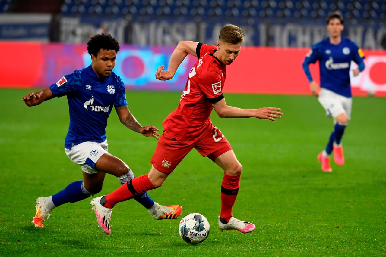 Mitchell Weiser del Leverkusen avanza con el balón pegado al pie pese a la marca pegajosa de Weston McKennie.
