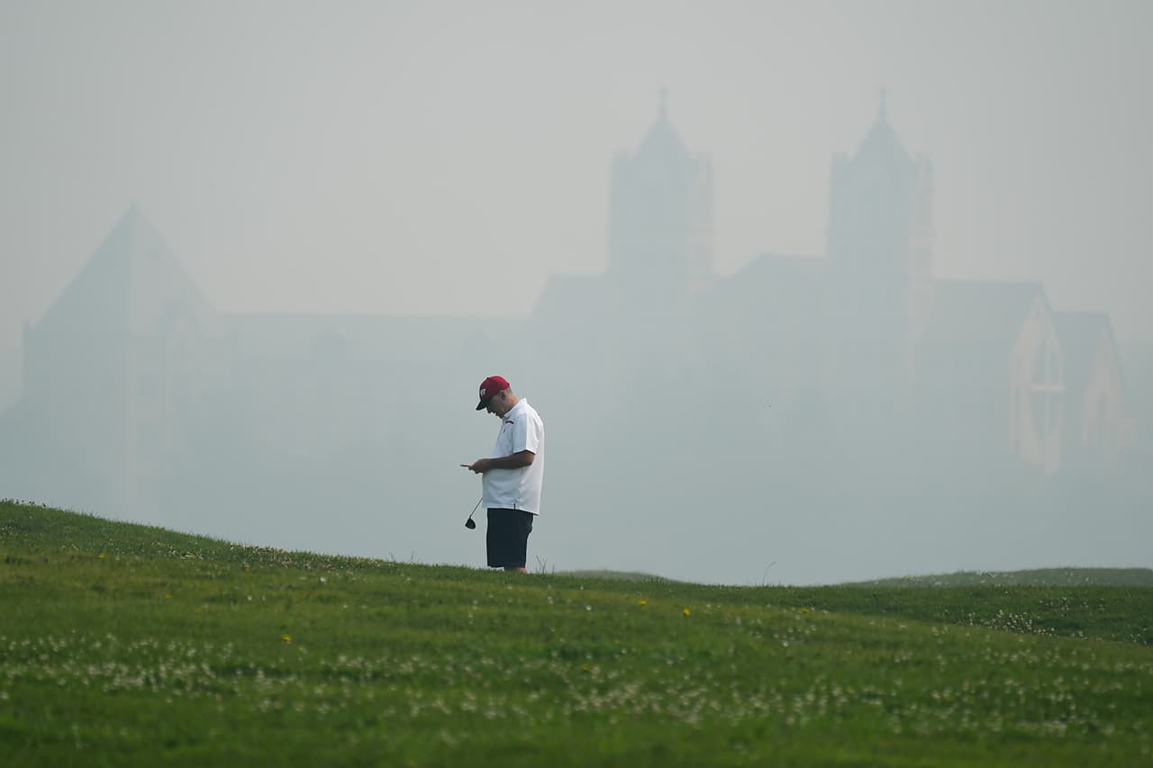 Un golfista revisa su tarjeta de puntuación en el campo de golf Willow Hills durante la mala calidad del aire debido al denso humo de los incendios forestales canadienses en Northbrook, Illinois, el jueves 16 de julio de 2026.Los expertos sugieren que las personas usen mascarillas de alta calidad cuando estén al aire libre, aunque no brindan una protección perfecta.