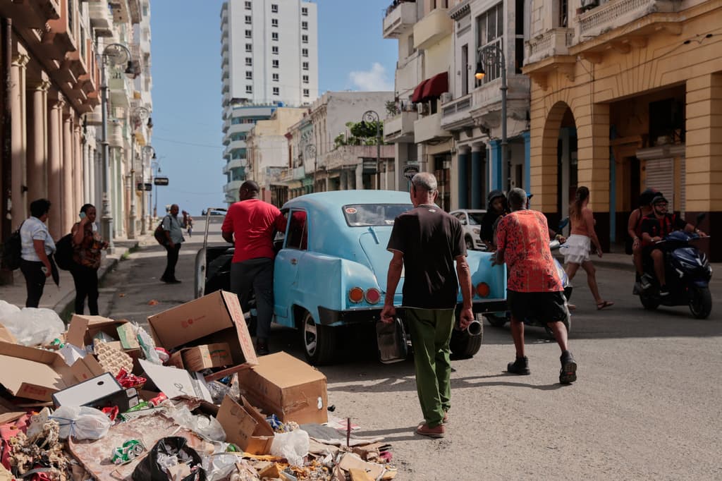 Varias personas empujan un coche clásico americano averiado junto a un montón de basura en La Habana, Cuba, el miércoles 17 de junio de 2026. (AP Foto/Jorge Luis Banos)