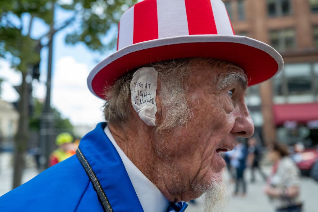 MILWAUKEE, WISCONSIN - JULY 17: A Donald Trump supporter and performer places a bandage over his ear in reference to Trump's wound at the Republican National Convention (RNC) on the third day of the convention on July 17, 2024 in Milwaukee, Wisconsin. Security throughout downtown Milwaukee remains high following the assassination attempt on former President Donald Trump over the weekend. Thousands of delegates, politicians and the Republican faithful are arriving into the traditionally Democratic city over the next few days for the annual convention which will conclude with former President Donald Trump accepting his party's presidential nomination. The RNC takes place from July 15-18. (Photo by Spencer Platt/Getty Images)
