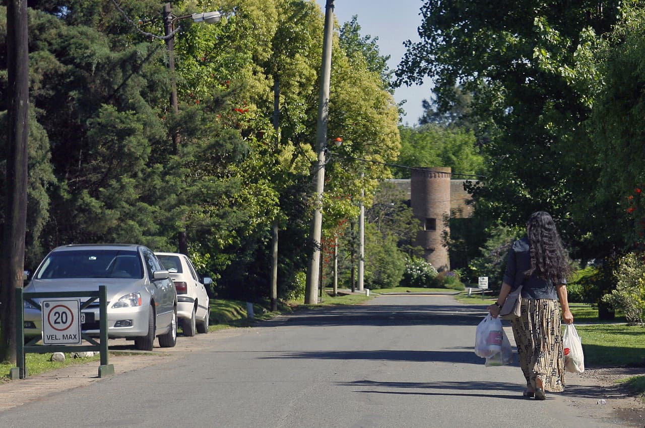 Una criada carga las compras a la entrada de un barrio privado.