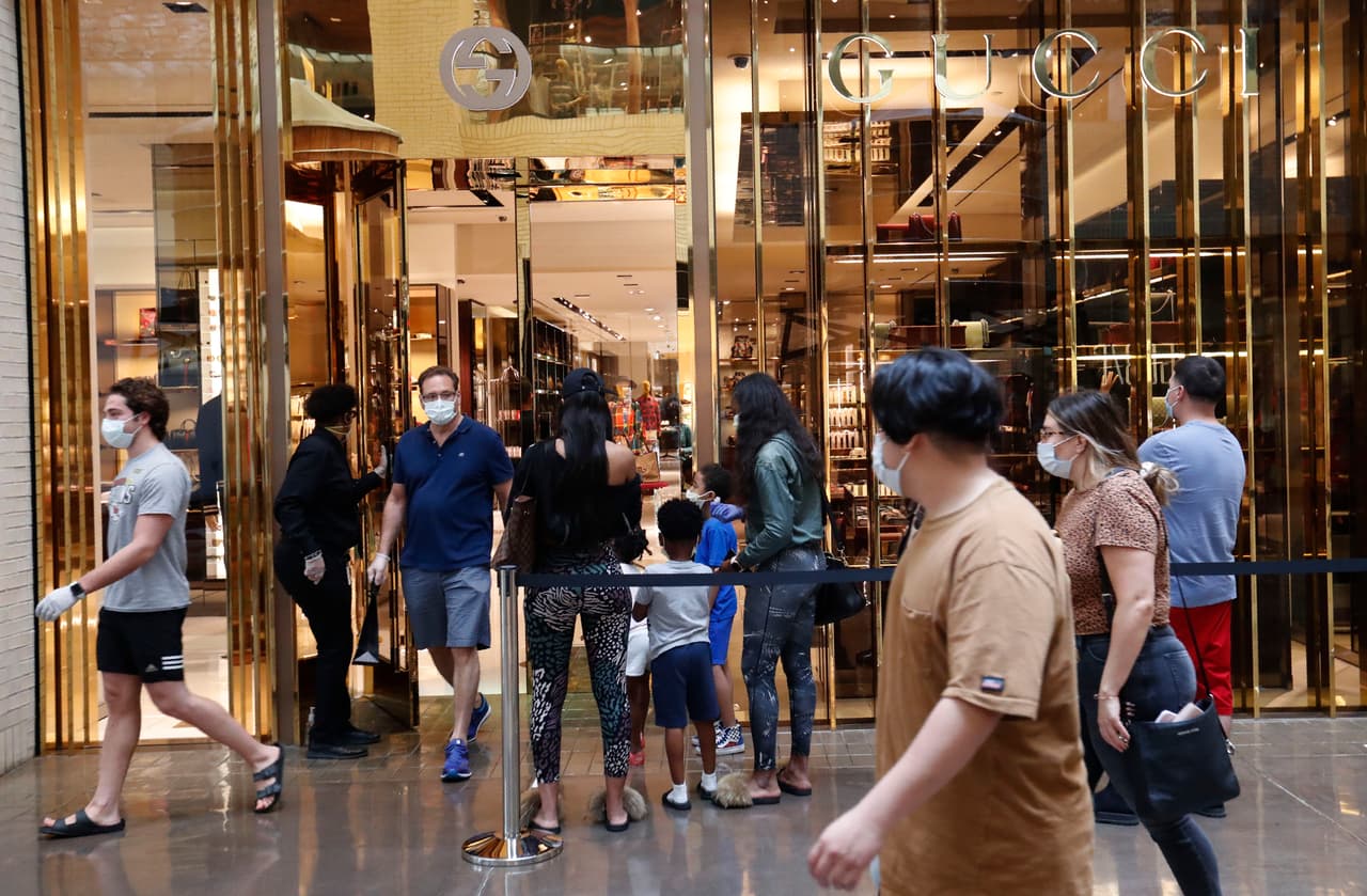 Un comprador deja una tienda mientras otros esperan para ingresar al North Park Mall en Dallas, el sábado 2 de mayo de 2020.
