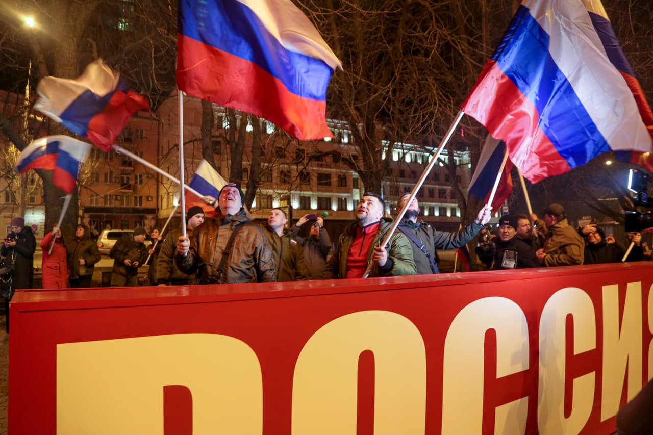 Manifestantes llevan banderas rusas tras un cartel que rice "Rusia" en el centro de Donetsk, territorio controlado por militantes a favor de Moscú.
<br>
