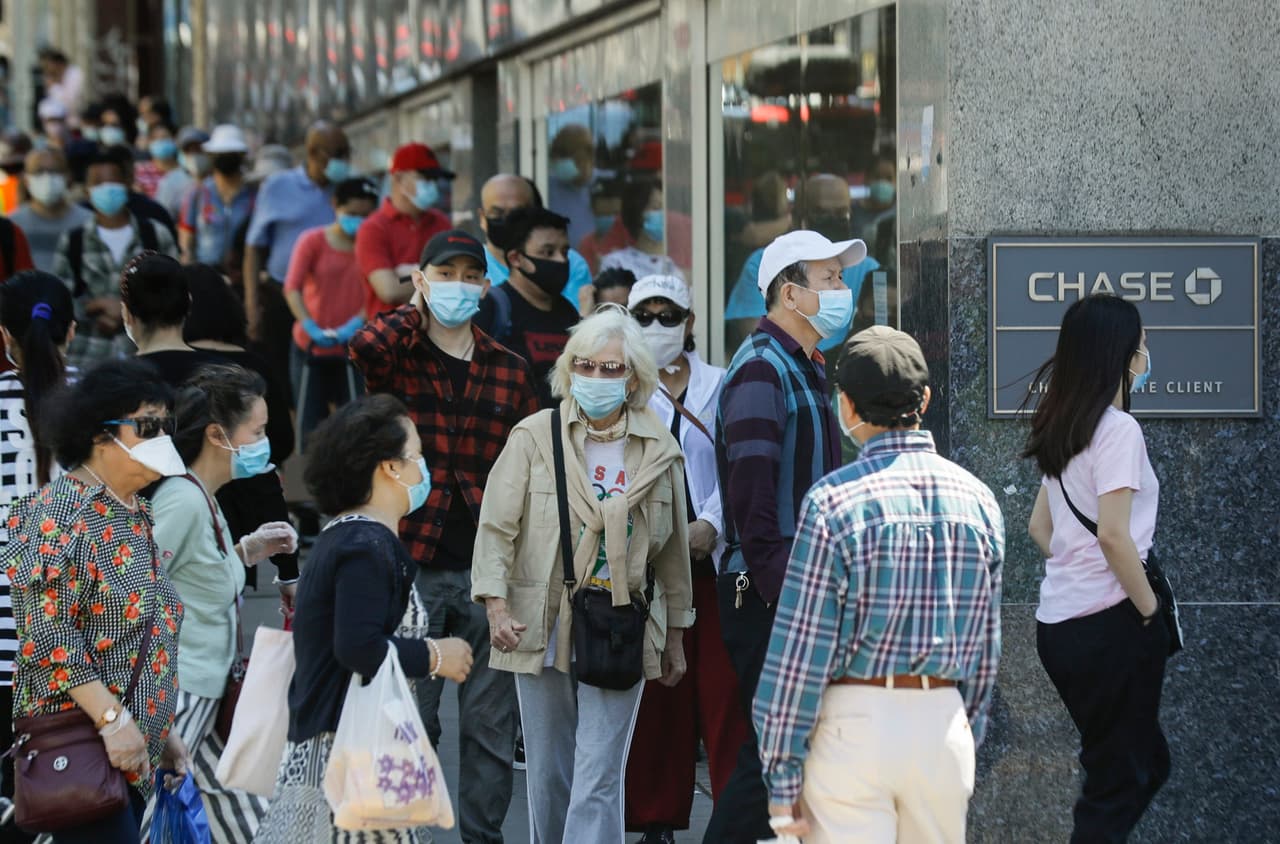 Clientes con máscaras protectoras esperan para ingresar a un banco, el lunes 8 de junio de 2020, en Queens, Nueva York. Después de tres meses sombríos, la ciudad de Nueva York intentará pasar la página tras el golpe del coronavirus.