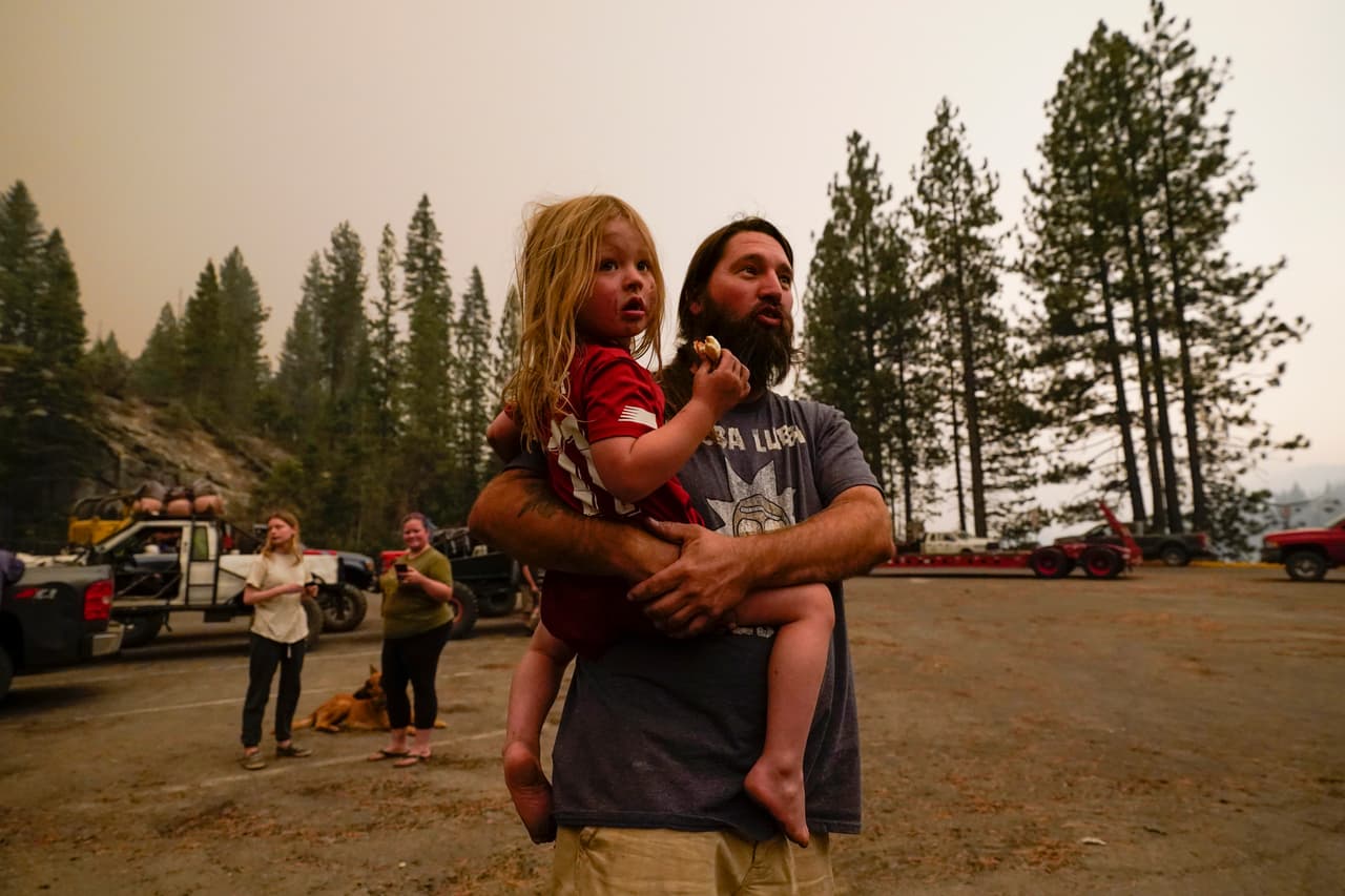 Jeremy Hedrick
<b> </b>sostiene a su hijo Jeep mientras el humo del Creek Fire llena el aire en un puerto deportivo, donde los campistas estaban retenidos debido a carreteras intransitables, causadas por el incendio en Shaver Lake, California.
<br>