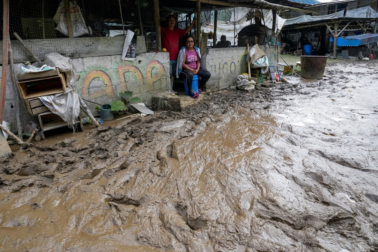 Los residentes se sientan en sus casas a lo largo de una carretera inundada por un deslizamiento de tierra causado por fuertes lluvias en Baños, Ecuador, 17 de junio de 2024.