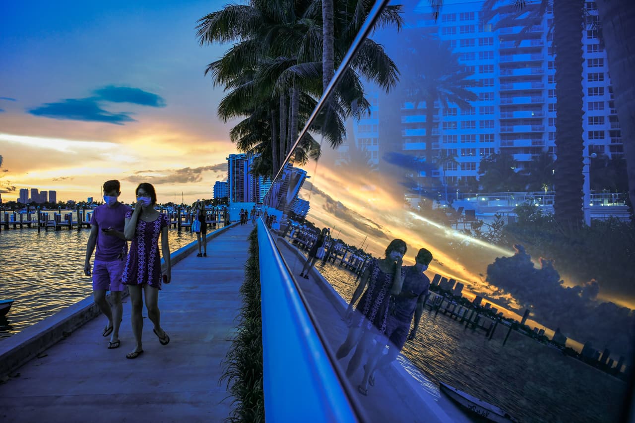 Una pareja camina en South Bay, en Miami Beach, usando tapabocas, una medida requerida por el gobierno local a expensas de multas económicas.