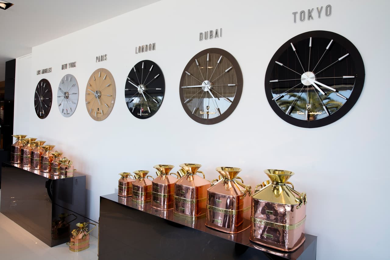 Los relojes diseño de la marca Lamborghini cuelgan de una pared del garaje, encima de unos muebles decorados con unas vasijas de cobre y oro.