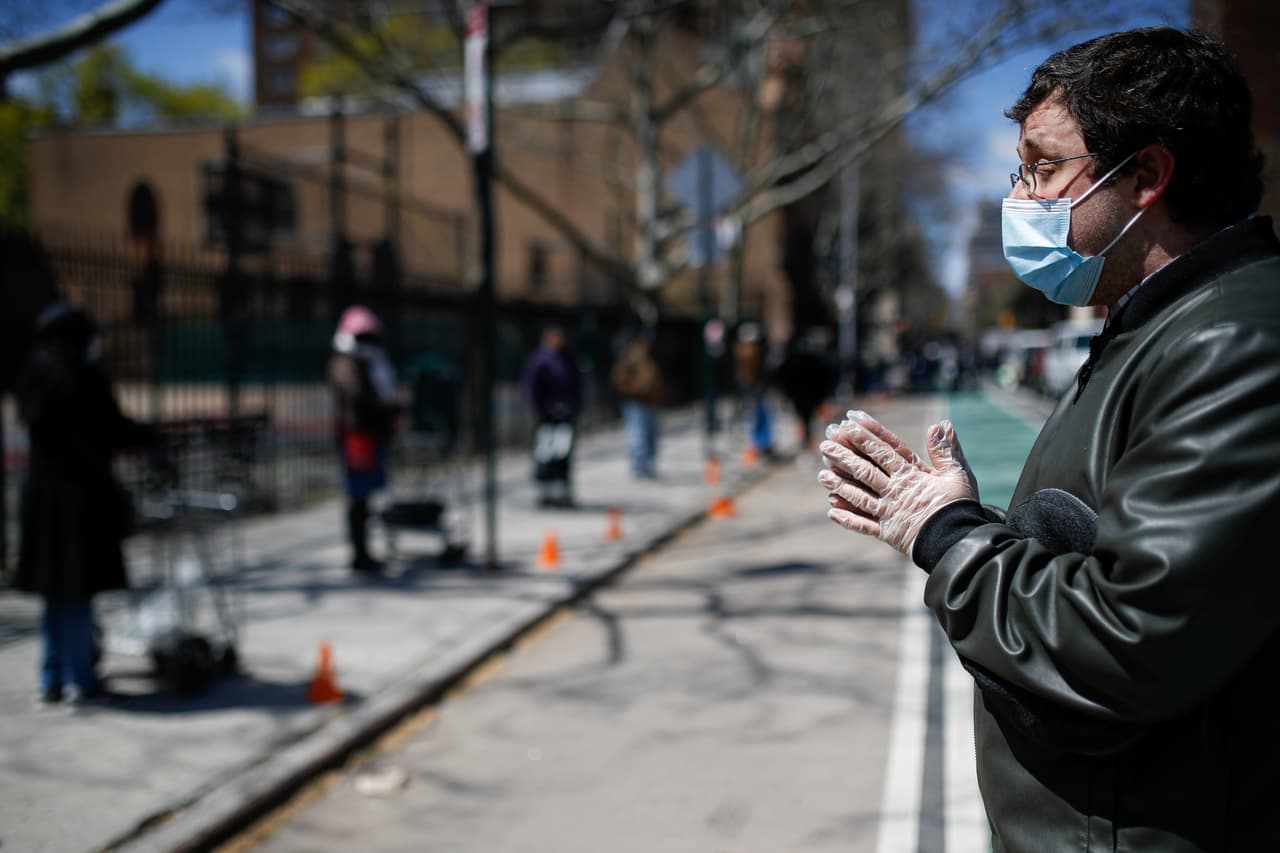 <b>11 de abril - </b>Christopher Love, gerente general de la Misión de la Misericordia de la Alianza dirige una oración junto a una fila de visitantes que esperan donaciones de alimentos en la Iglesia de la Comunidad Manor
