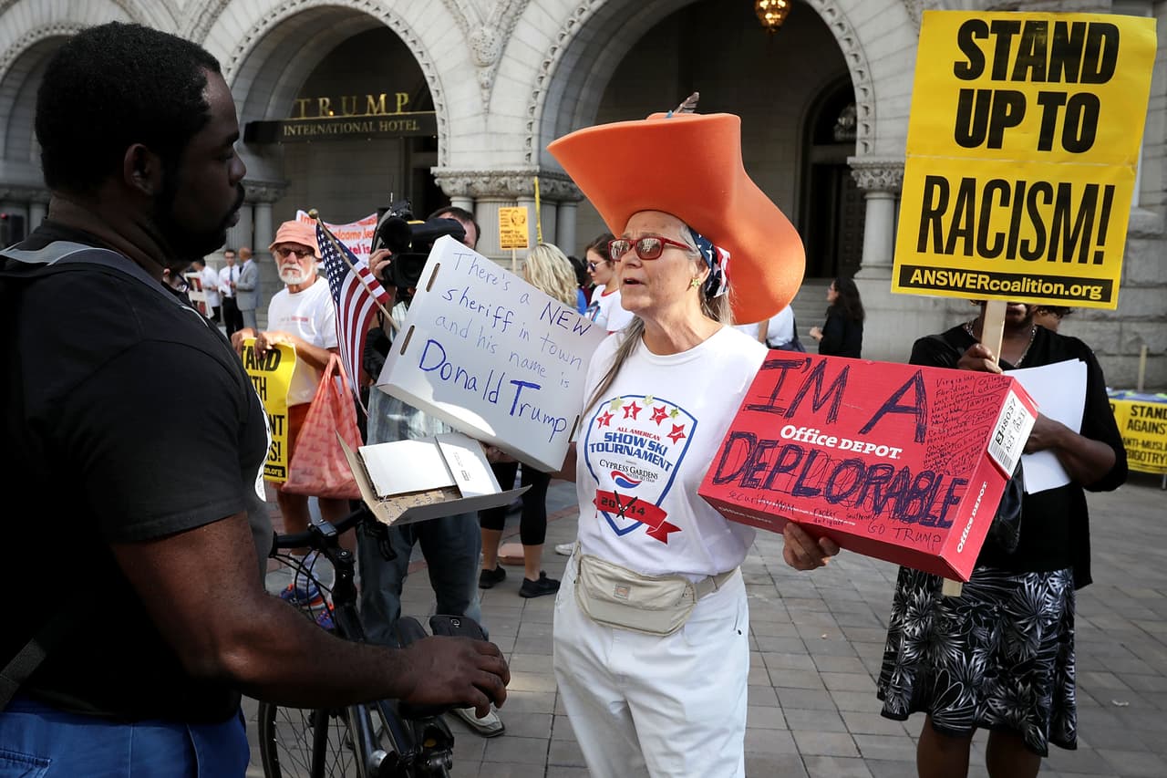 Una discusión se desata entre manifestantes y seguidores frente al recien inaugurado Hotel Internacional Trump en Washington, DC, el 12 de septiembre de 2016. Una seguidora del candidato sostiene un aviso que lee: "Soy una deplorable".