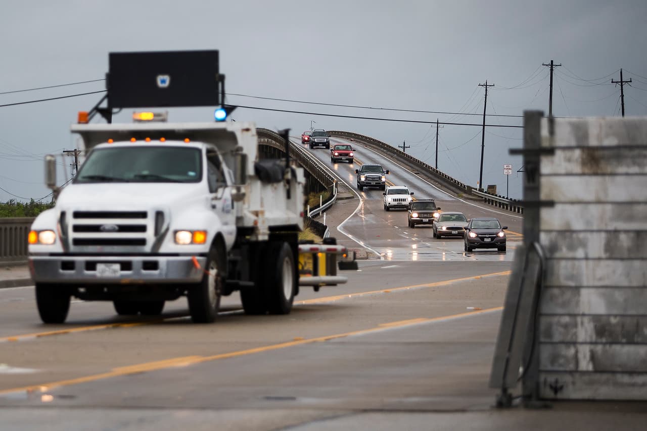 Unas filas de automóviles salen de Port Aransas, Texas, por una vía donde se instala un muro de contención preventivo.