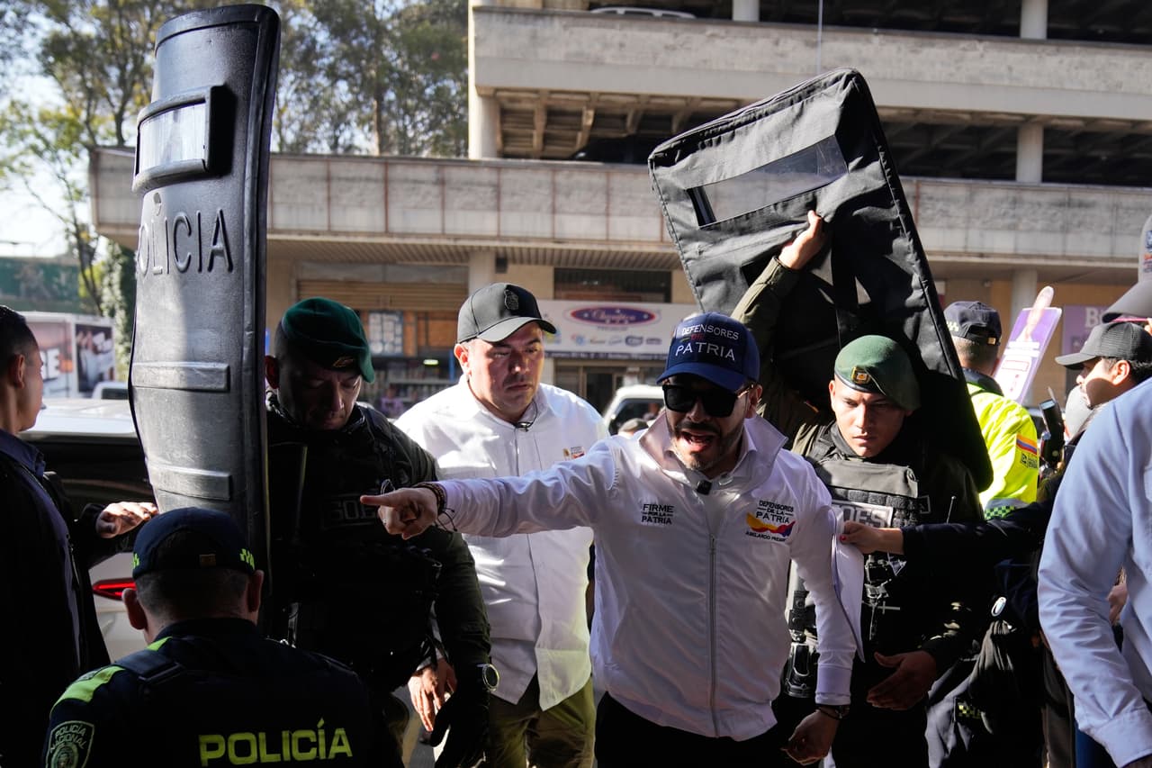 La policía sostiene escudos que protegen al candidato presidencial Abelardo de la Espriella mientras señala durante un mitin de campaña en Corabastos, el mayor centro de distribución de alimentos, en Bogotá, Colombia, el sábado 28 de febrero de 2026. (Foto AP/Fernando Vergara)