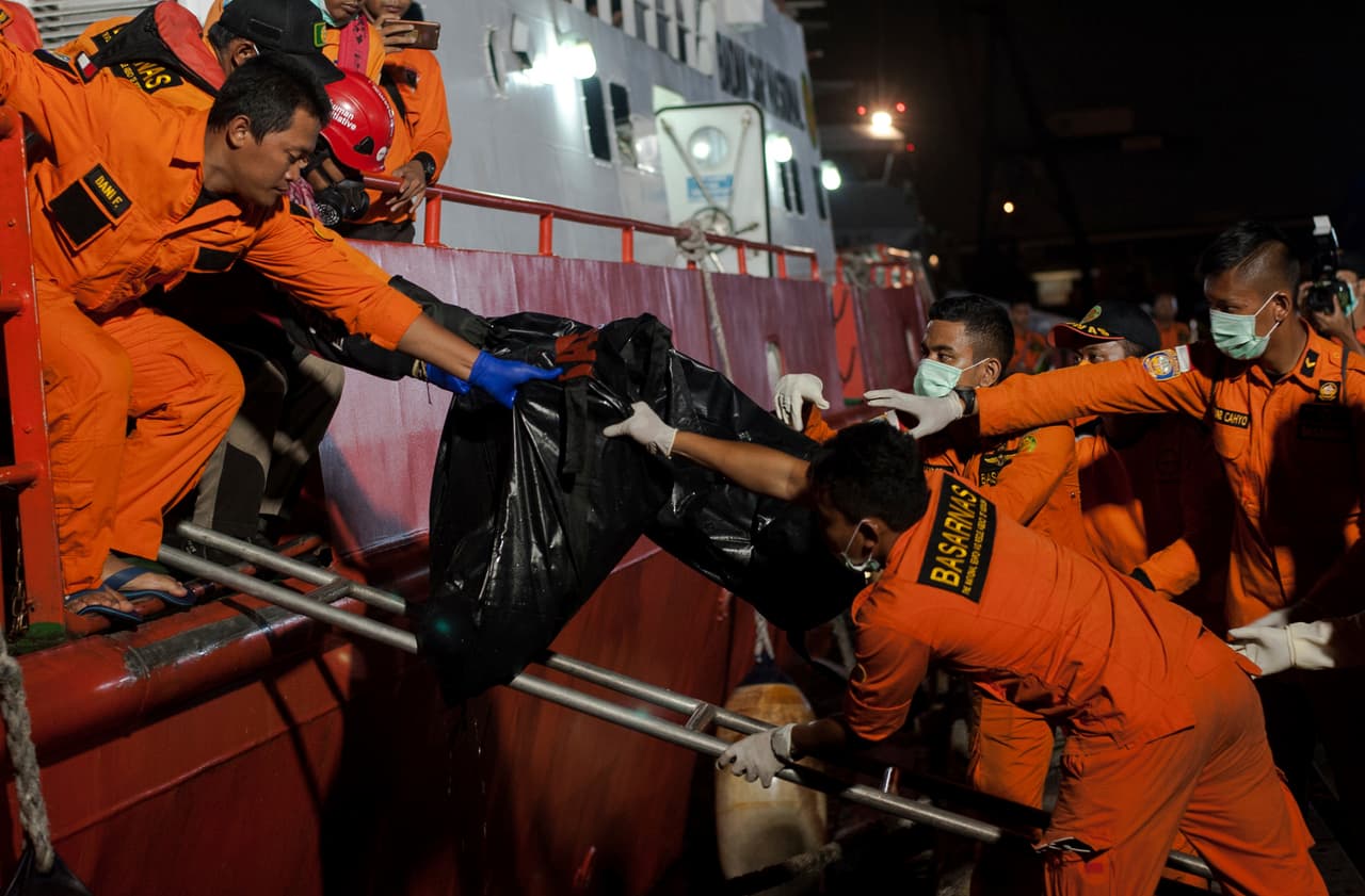 Los rescatistas entregan bolsas de cadáveres que contienen los restos de las víctimas del avión Lion Air que se estrelló a sus colegas al llegar al puerto de Tanjung Priok en Yakarta, Indonesia, el sábado.