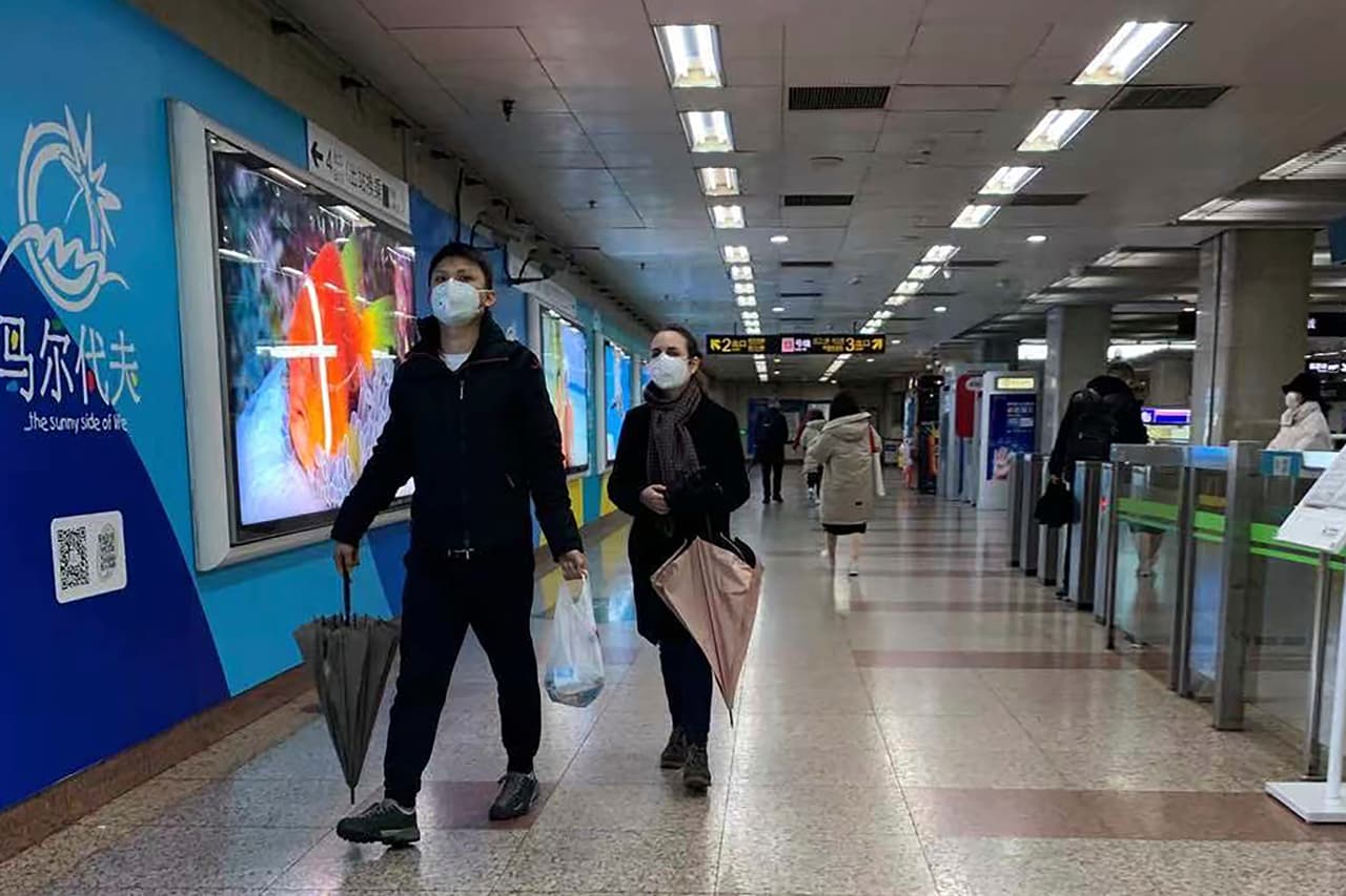 Unas personas usando un cubrebocas caminan por una estación de metro desierta en Shanghai, China, el domingo 26 de enero de 2020, mientras persiste el temor por el coronavirus.