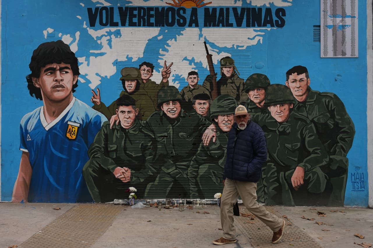 Un hombre camina frente a un mural callejero que representa a la fallecida estrella del fútbol Diego Maradona y a veteranos de la guerra de 1982 entre Argentina y Gran Bretaña por las Islas Malvinas (conocidas en inglés como
<i>Falkland Islands</i>), en Buenos Aires, Argentina, el miércoles 15 de julio de 2026.