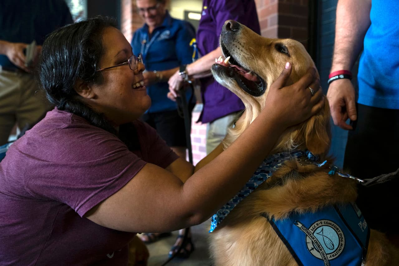 Una mujer en El Paso, Texas, acaricia un perro de terapia el 14 de agosto de 2019, en un monumento a las 22 personas asesinadas en un tiroteo masivo en el lugar.