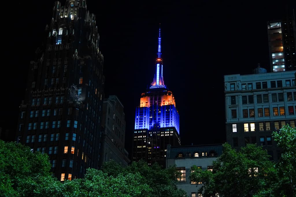 Silente, el legendario Empire State presumía los colores del equipo de los Knicks, en una noche oscura para los fans.