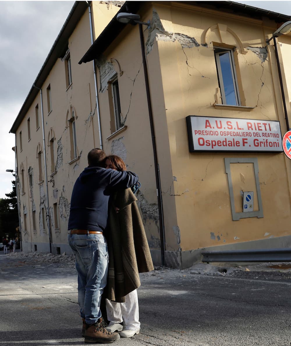 Este hombre abraza a una mujer frente al hospital de Amatrice, que sufrió también severos daños con el sismo