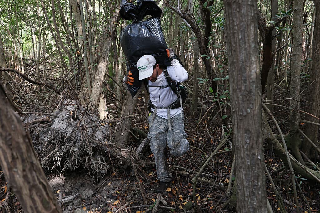 Otazo lleva sobre sus hombros la basura que halla en los manglares.