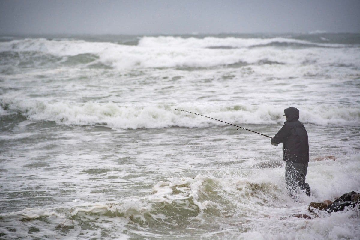Una persona pesca desde la orilla mientras las olas azotan la costa durante una tormenta Nor’Easter en Scituate, Massachusetts, el 26 de septiembre de 2026.