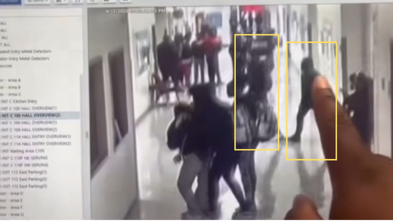 La persona mantiene el dedo sobre la pantalla mientras señala cómo el joven, que
<b>parece llevar parte de la cabeza cubierta con la capucha de una sudadera o chamarra</b>, cruza el pasillo entre los alumnos, al tiempo que
<b>otro joven camina en la misma dirección, de frente a él.</b>