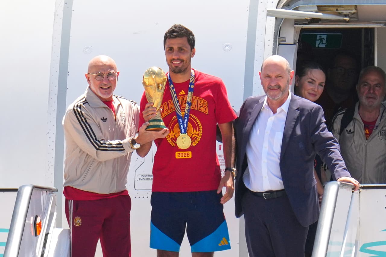 Rodrigo Hernández, de España, sostiene el trofeo de la Copa del Mundo junto al seleccionador español Luis de la Fuente (izquierda) y el presidente de la Real Federación Española de Futbol, Rafael Louzan, a su llegada al aeropuerto de Madrid el lunes 20 de julio de 2026, tras la victoria de España sobre Argentina en la final del Mundial.