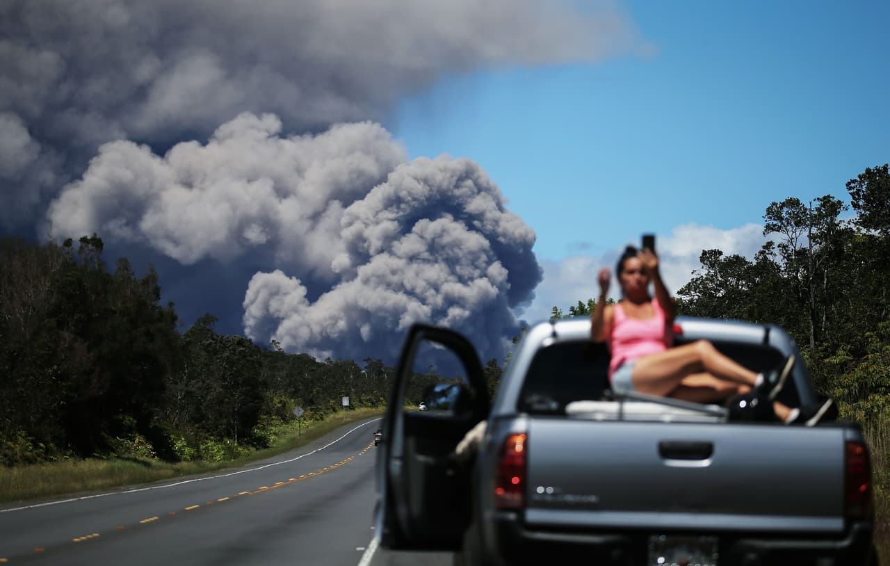 Una mujer se toma un ‘selfie’ con el volcán de fondo desde una carretera. La ceniza se ha convertido en un peligro para los residentes de la Isla Grande de Hawaii, quienes venían enfrentando las emisiones de gas volcánico y la lava, que hasta ahora ha destruido 37 casas y forzó la evacuación de unos 2,000 residentes.